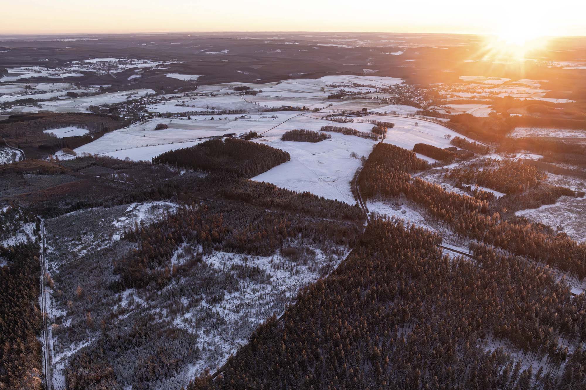 Saint-Hubert bij zonsondergang met besneeuwde bossen en plateaus in de winter