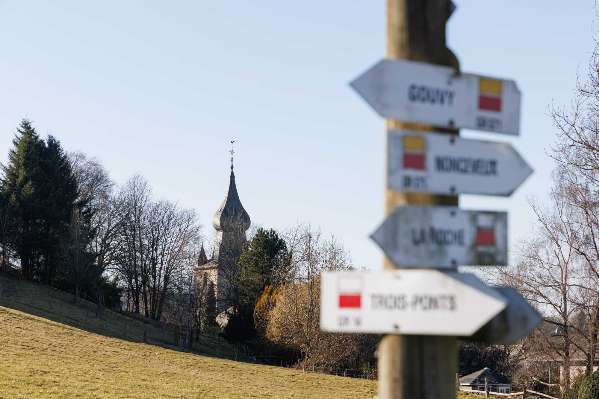 Wandelborden in Lierneux met de kerktoren op de achtergrond in helder winterweer.