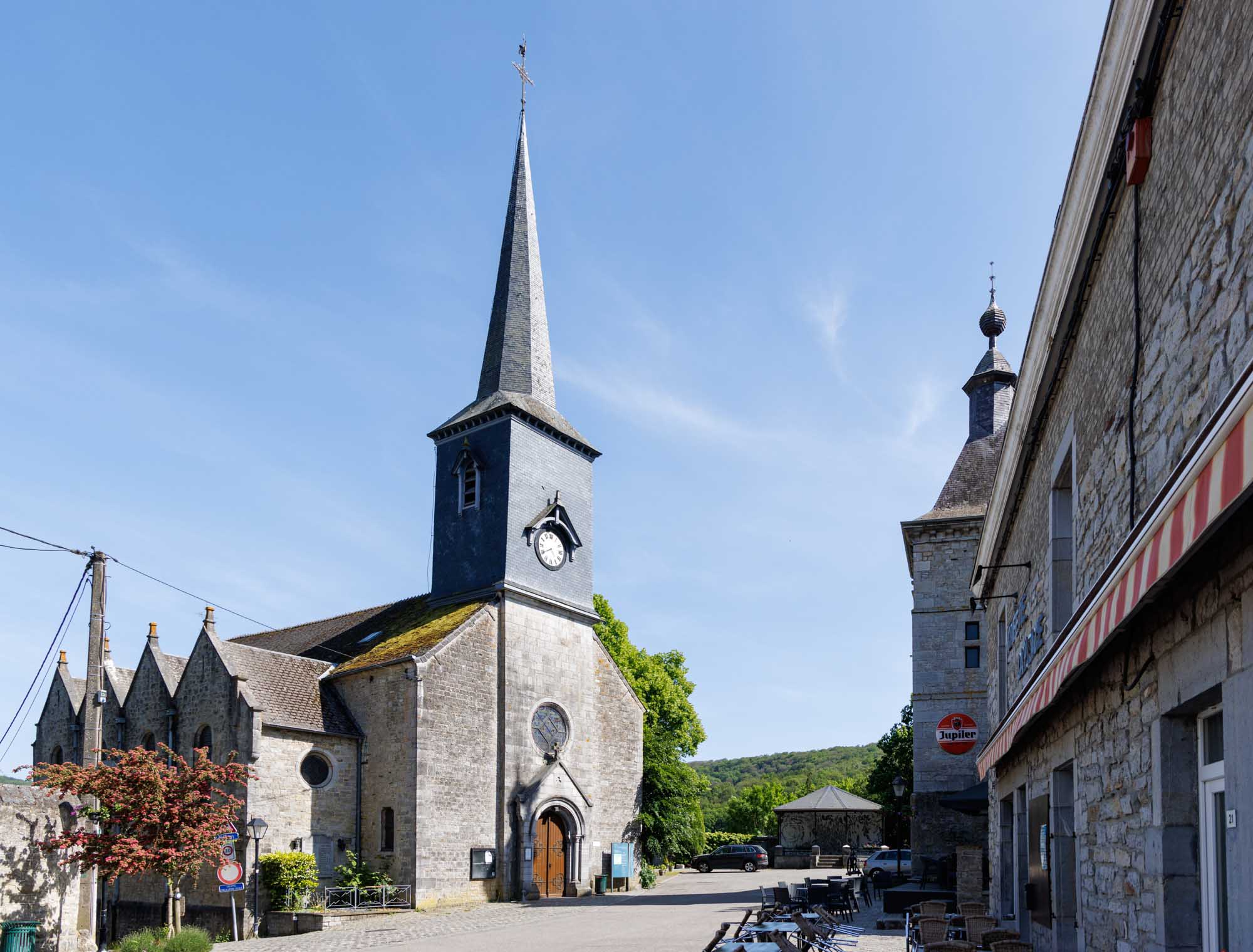 Kerk van Viroinval op het dorpsplein, met stenen huizen en heldere lucht.