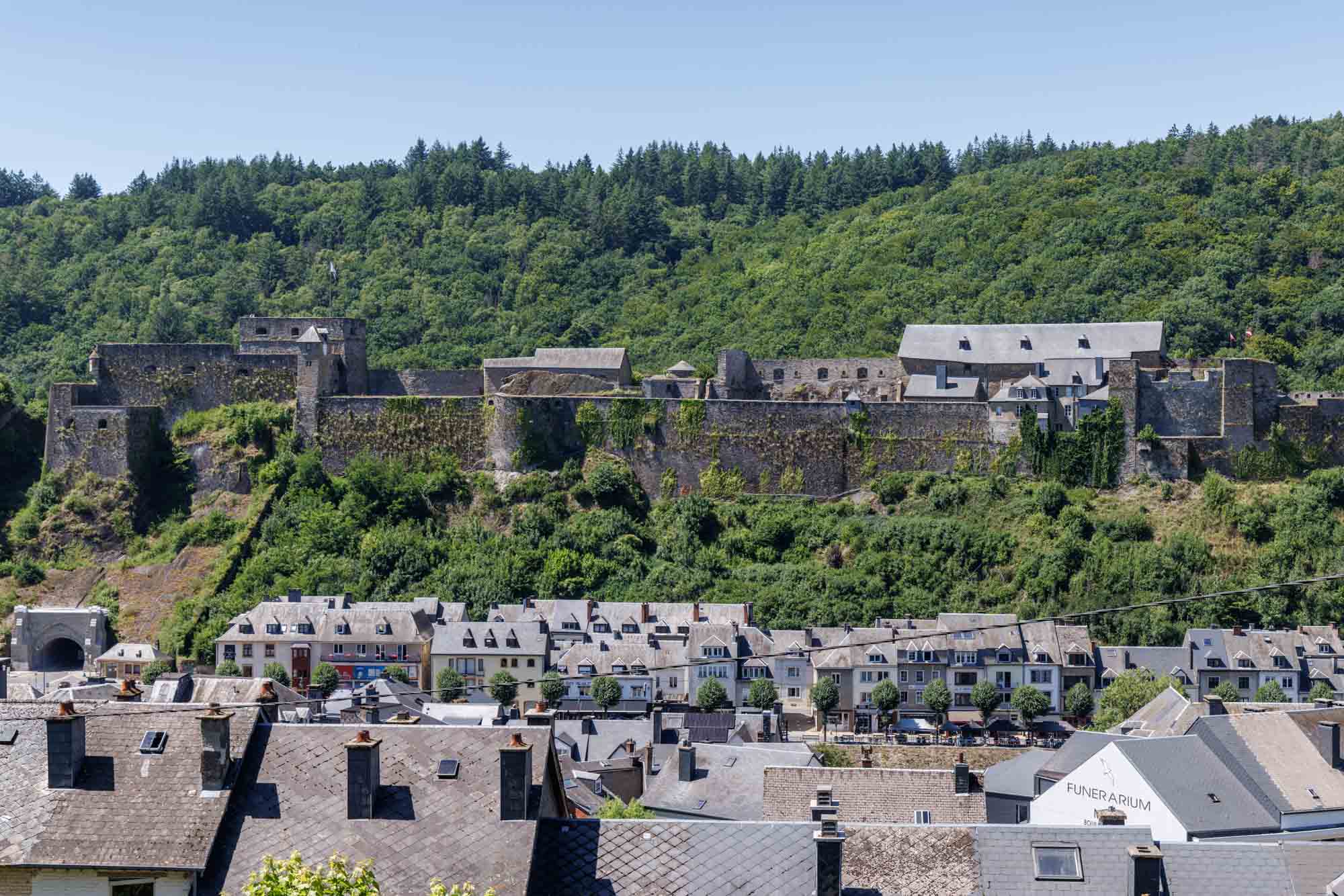Château-fort de Bouillon op zijn rotsplateau boven de daken van het stadscentrum in de zomer